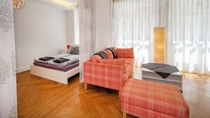 Camera da letto moderna con un letto, una poltrona, un tavolino e un'ampia finestra con tende leggere.