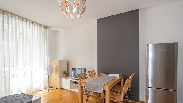 Un soggiorno moderno con zona pranzo, un frigorifero grande e un televisore.