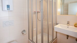 Un bagno moderno con doccia vetrata, lavandino bianco e specchio sopra il lavandino.