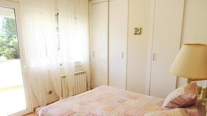 A bedroom with a bed, a lamp, a window with curtains, and a radiator. - Family house 5 minutes from the beach (Calella de Palafrugell)