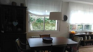 A dining area with a table, chairs, a cabinet, and a window with curtains. - Family house 5 minutes from the beach (Calella de Palafrugell)