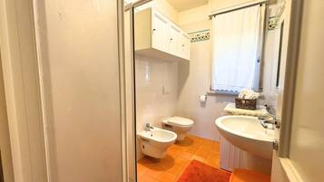 Ein Badezimmer mit einer Bidet-Einrichtung, Toilette und Waschbecken.