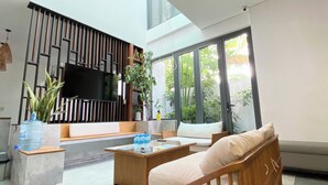 Una sala de estar moderna con un sofá, una mesa de centro y un televisor de pantalla plana montado en una pared con listones de madera verticales.