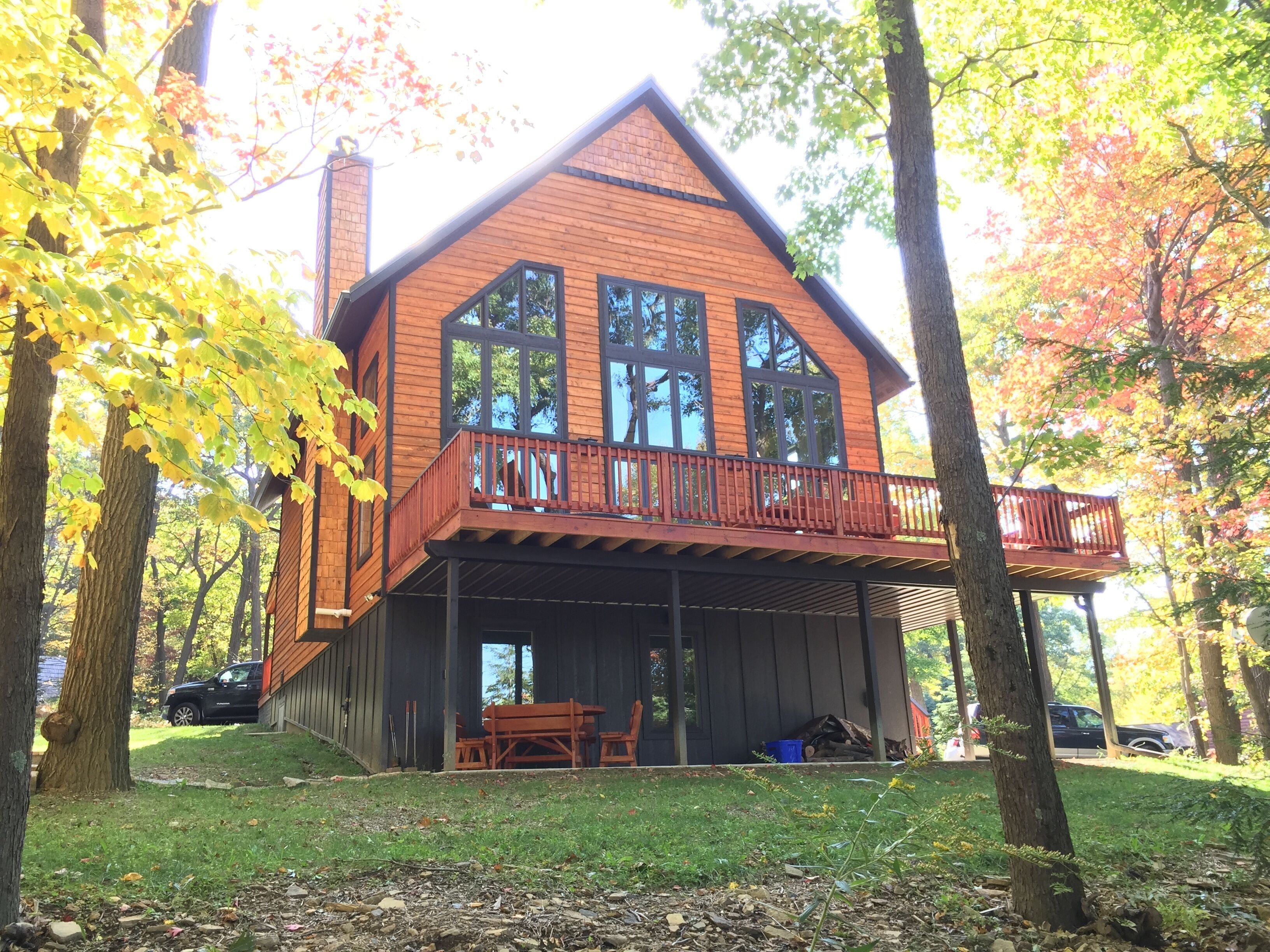 Une cabane en bois à deux étages, dotée d’un balcon et entourée d’arbres.