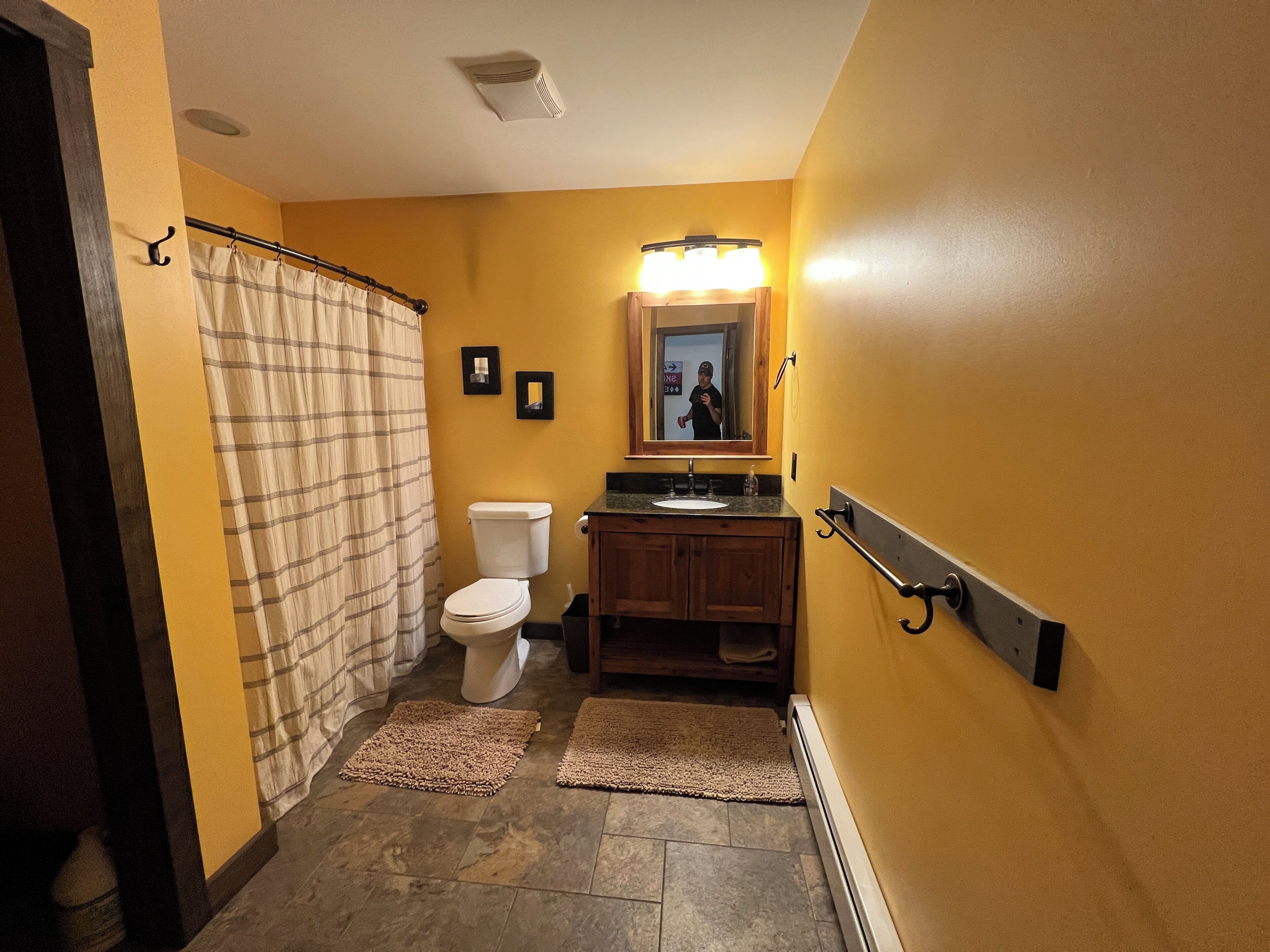 A bathroom with a toilet, sink, mirror, and shower curtain.