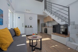 Et moderne opholdsrum med sofa, spisebord, et køkken og en trappe.