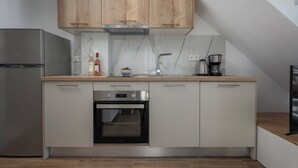 A modern kitchen with wooden cabinets, a built-in oven, a stainless steel refrigerator, and a marble backsplash. - SLV Irida Apartment (Pangaio)
