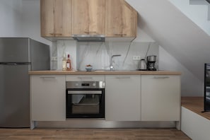 A modern kitchen with wooden cabinets, a built-in oven, a stainless steel refrigerator, and a marble backsplash. - SLV Irida Apartment (Pangaio)