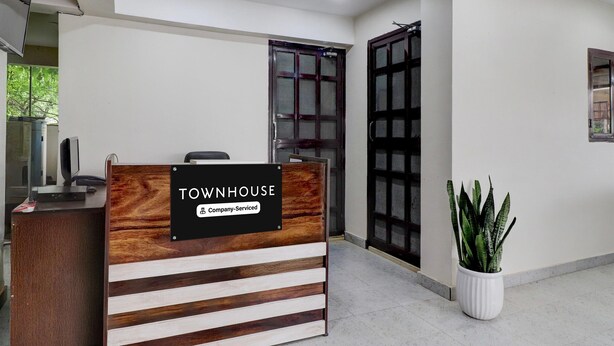 Un mostrador de recepción con un cartel que dice 'TOWNHOUSE' y una planta en maceta a su lado.