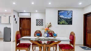Un comedor con una mesa de vidrio, sillas de madera y un jarrón decorativo.
