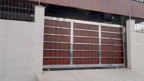 Puerta de garaje cerrada con estructura metálica, pared de concreto y suelo de baldosas.
