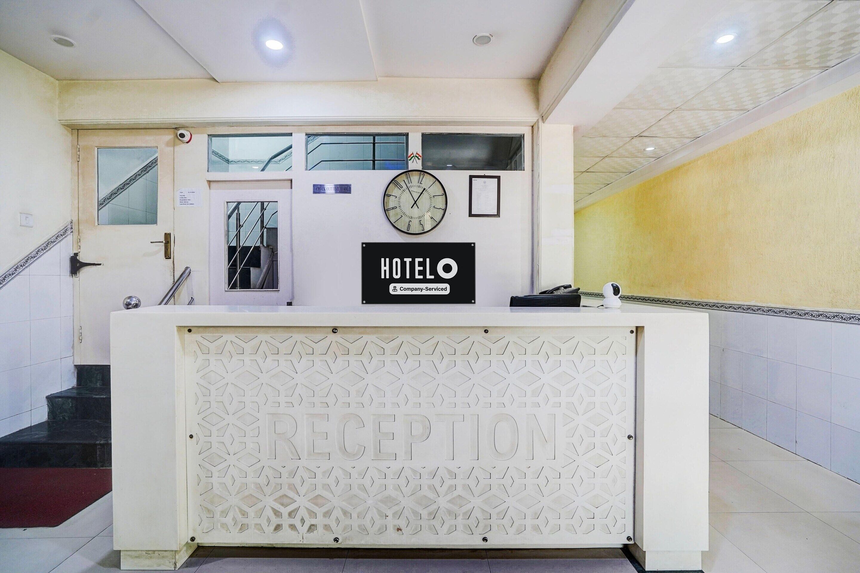 Una reception con una sveglia, una segnaletica che indica un hotel di servizio aziendale e una scala a sinistra.