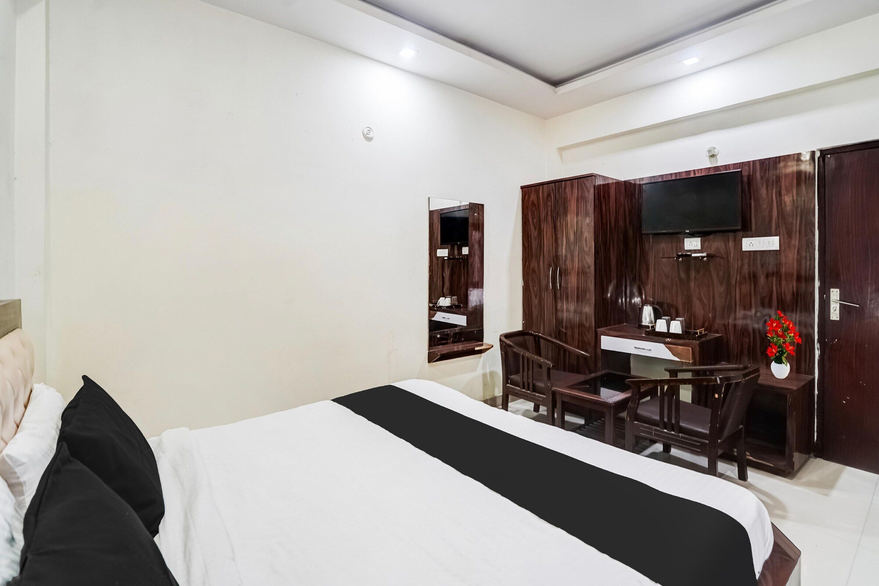 A hotel room with a bed, a desk, a chair, a TV, and a wardrobe.