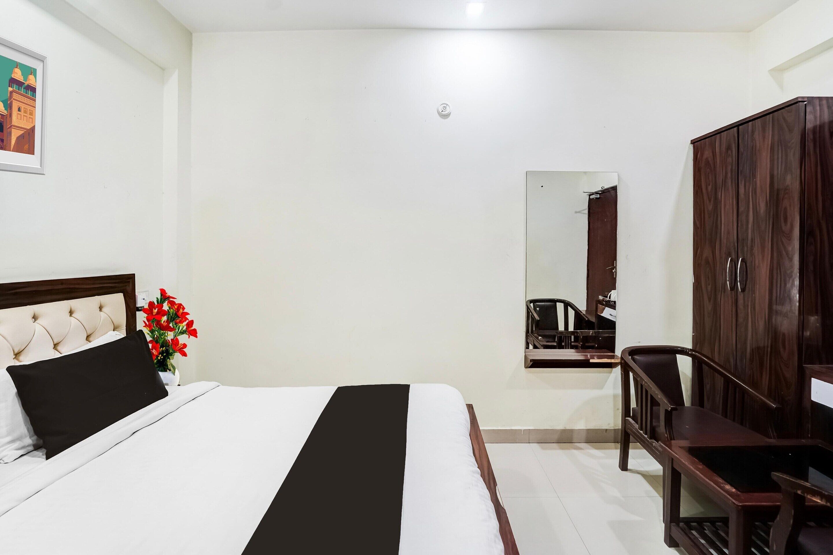 Een hotelkamer met een bed, een bureau, een kledingkast en een spiegel.