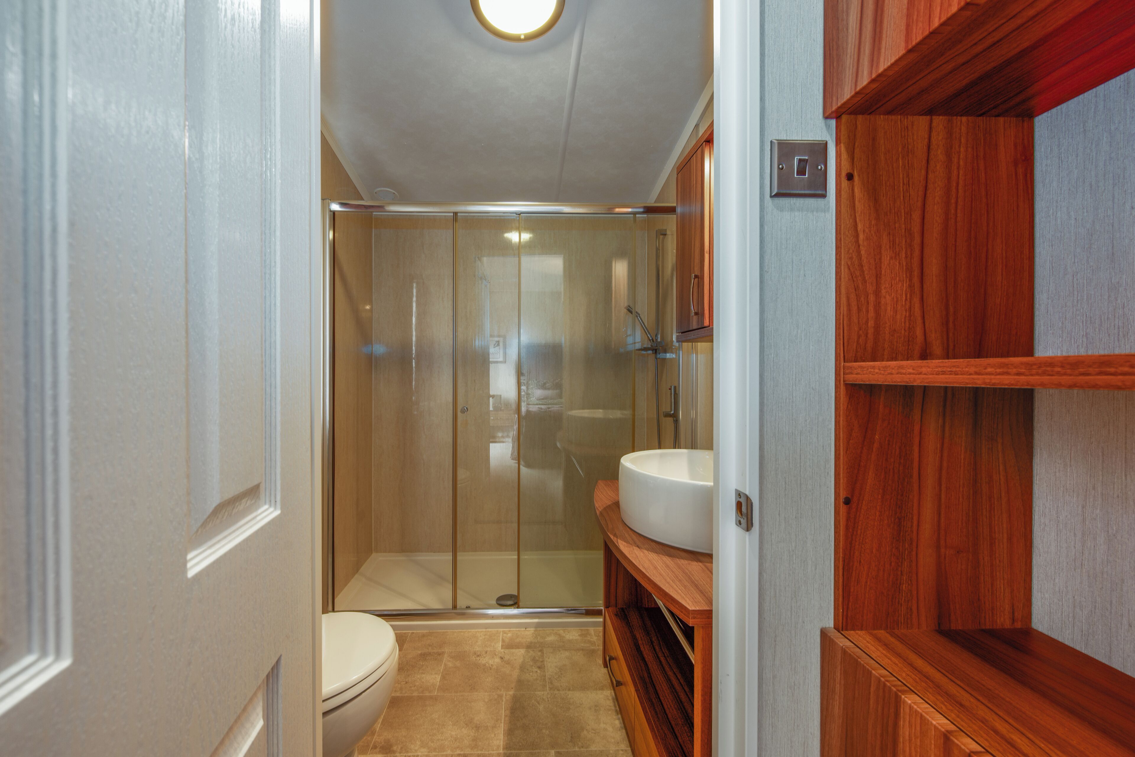A bathroom with a toilet, a glass-enclosed shower, and wooden cabinetry.