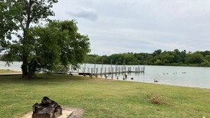 Un espace vert, un parc avec une jetée qui s’avance sur un lac, le tout entouré d’arbres.