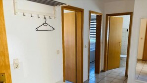 A hallway with a bench, wooden doors, and a hanging coat rack. - Ferienwohnung in Petersdorf auf Fehmarn (Fehmarn)