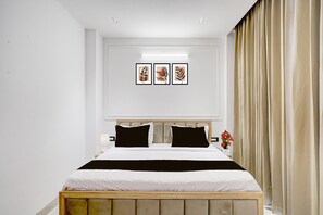 A bedroom with a bed, a nightstand, a lamp, and framed artwork on the wall.