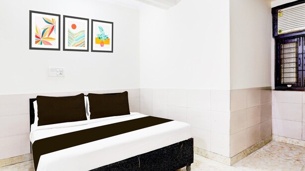 A bedroom with a bed, white walls, and three framed artworks. - Saver Doublehotel Welcome Inn (New Delhi)