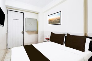 Quarto de hotel com uma cama, uma porta, um armário e um quadro na parede.
