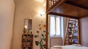 Un dormitorio con cama de madera, una estantería, una escalera y una ventana con cortinas.