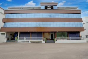 A modern building with a sign reading 'Collection.' It has multiple floors, large windows, and a covered entrance area with steps.