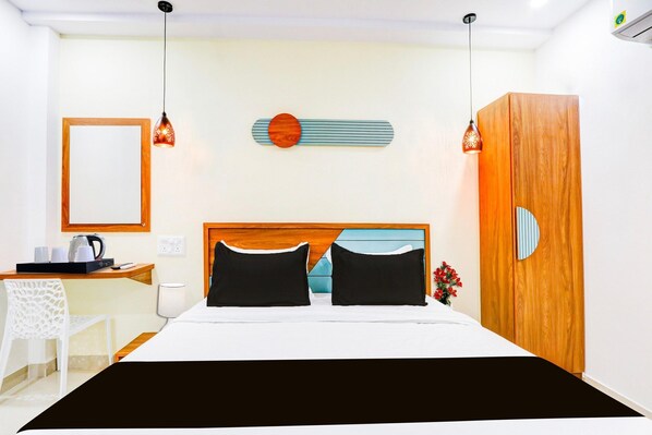 Een hotelkamer met een bed, nachtkastje, lamp en een houten garderobe.