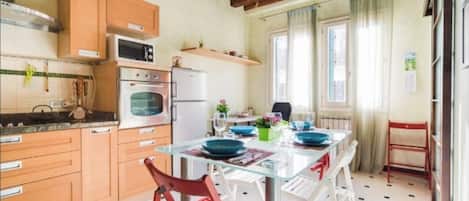 A kitchen with wooden cabinets, a microwave, an oven, and a dining table with chairs.