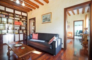 Ein Wohnzimmer mit einer Couch, einem Holztisch, einem Bücherregal und einem Bild an der Wand.