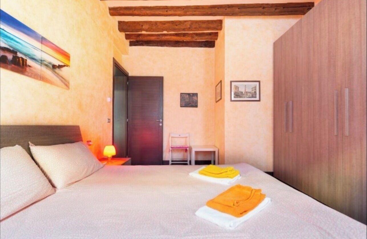 Ein Schlafzimmer mit Bett, Nachttisch, Stuhl, Kleiderschrank und einer Tür.