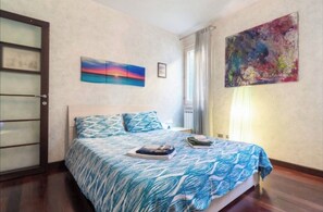 Ein Schlafzimmer mit einem Bett, einem Fenster mit Vorhängen und zwei Bildern an der Wand.