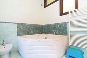Ein Badezimmer mit einer großen Badewanne, einem Bidet und einem kleinen Hocker.