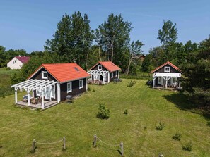 Eine Reihe von Ferienhäusern mit roten Dächern, Holzdecks und einem umzäunten Garten.