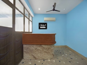 A room with a marble counter, a ceiling fan, a wall-mounted air conditioner, and a sign that reads 'Collection Company-Served.'