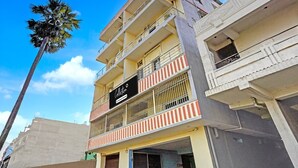 Un edificio de varios pisos con balcones, un letrero que dice 'Collection' y una palmera en primer plano.