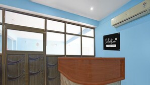 Zona de recepción con un mostrador de madera, un ventanal con vistas y un letrero en la pared.