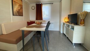 Um espaço compacto com mesa de jantar, sofá, televisão e um pequeno armário.