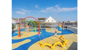 Uma área de lazer aquático com escorregadores e jatos de água, cercada por uma grade.