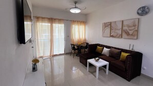 Ein Wohnzimmer mit einer Couch, einem Couchtisch, einem an der Wand montierten Fernseher und einem Deckenventilator.