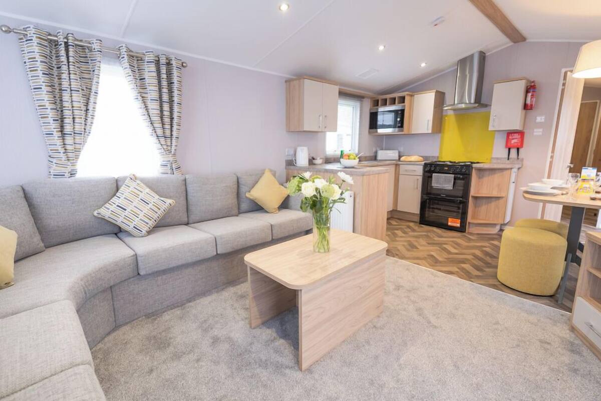 A modern living area with a sofa, a coffee table, and a kitchen in the background.