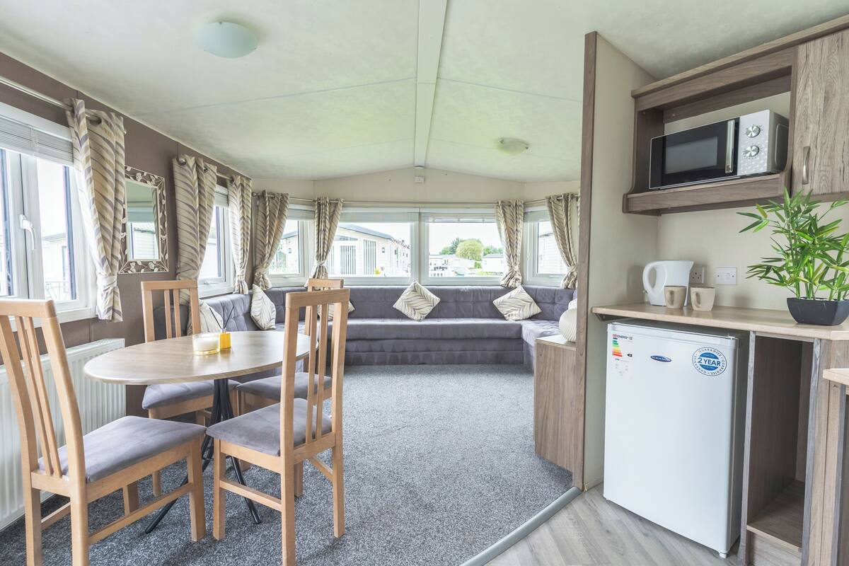 A compact kitchen with a microwave, refrigerator, and seating area.
