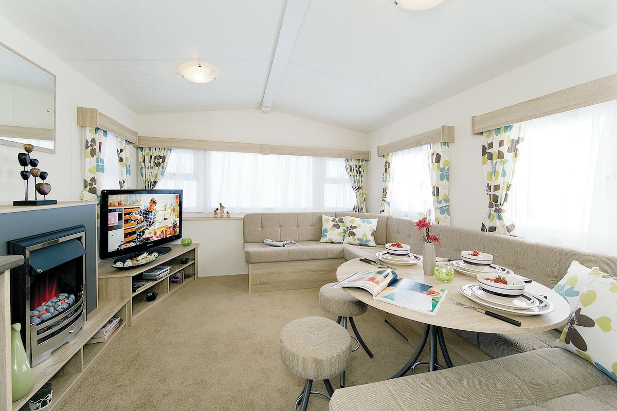 A cozy living room with a fireplace, sofa, dining table, and TV.
