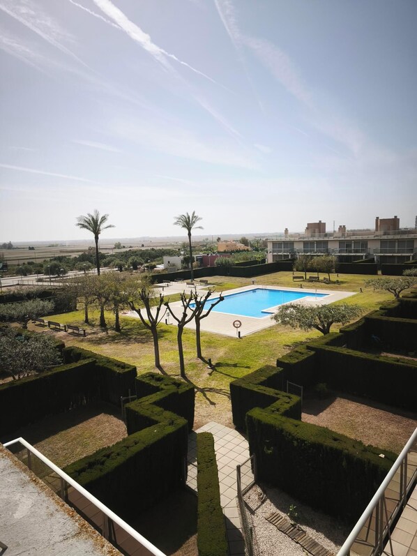 A pool area with a clear view of the surrounding landscape, including distant buildings and a clear sky. - APARTMENT WITH ROOF TERRACE L'AMPOLLA (L'Ampolla)