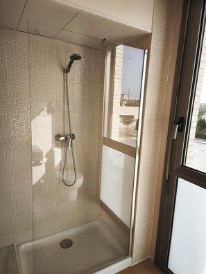 A shower with a glass door, a window, and a view of the outside. - APARTMENT WITH ROOF TERRACE L'AMPOLLA (L'Ampolla)