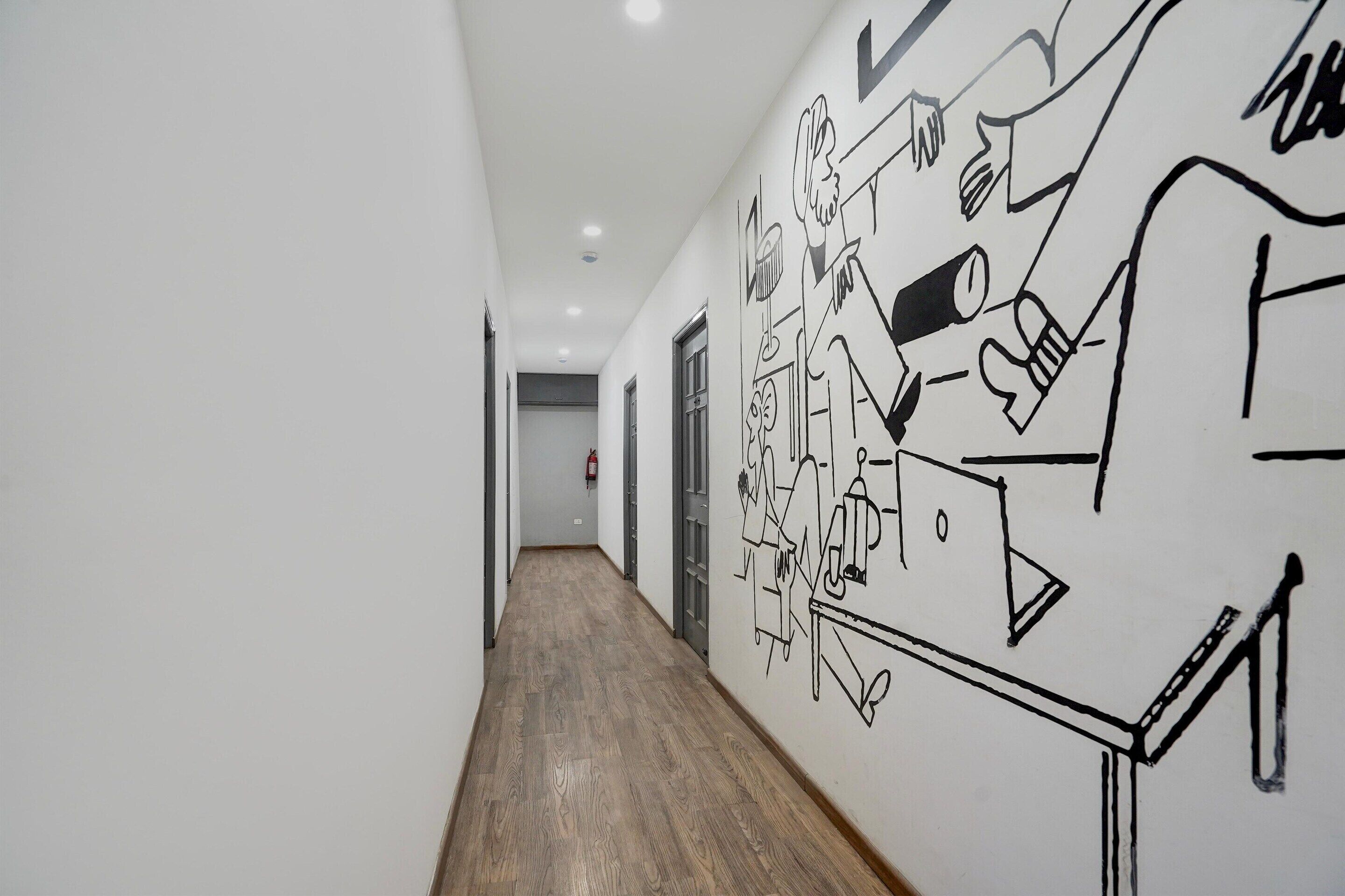 A hallway with a wooden floor and a wall with black line drawings.