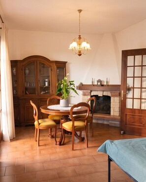 Ein Essbereich mit Holztisch und -stühlen, einer Chandelierleuchtre, einem Kamin und einem Schrank.