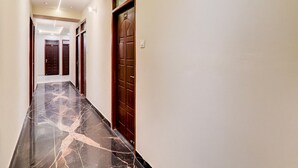 A hallway with marble flooring, wooden doors, and recessed lighting.