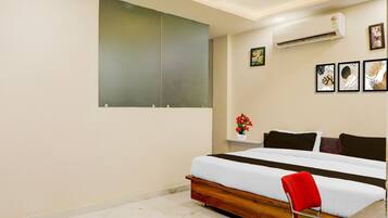 A modern bedroom with a bed, a red chair, a wall-mounted air conditioner, and framed artwork.