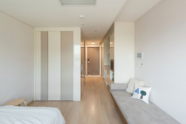 A modern hotel room with a bed, a sofa, a small table, and a walk-in closet.