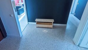 En gang med en træbænk, en dør og en rød væg i baggrunden.
